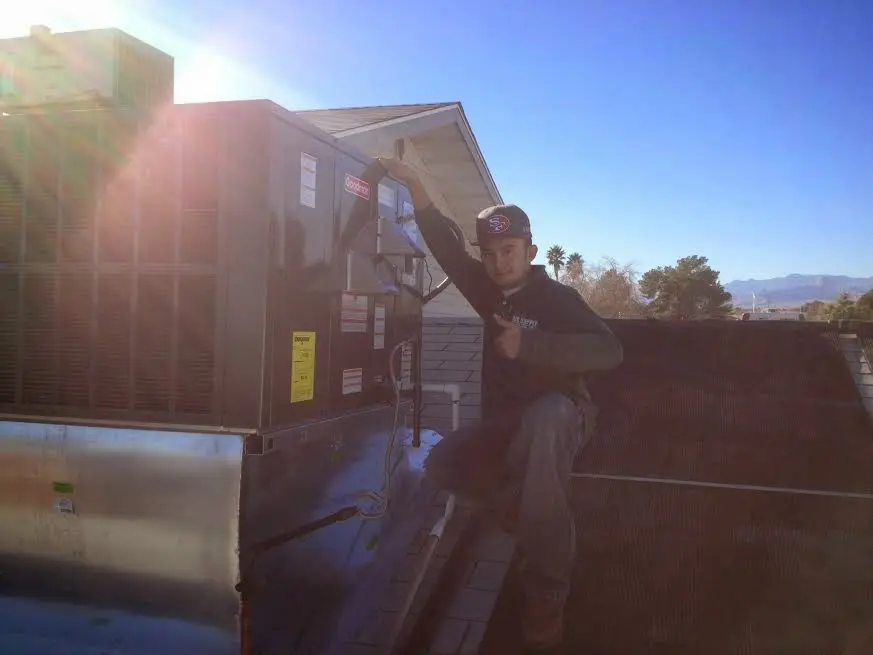 HVAC technician performing Air Duct Repair on a rooftop unit in Lake Jackson